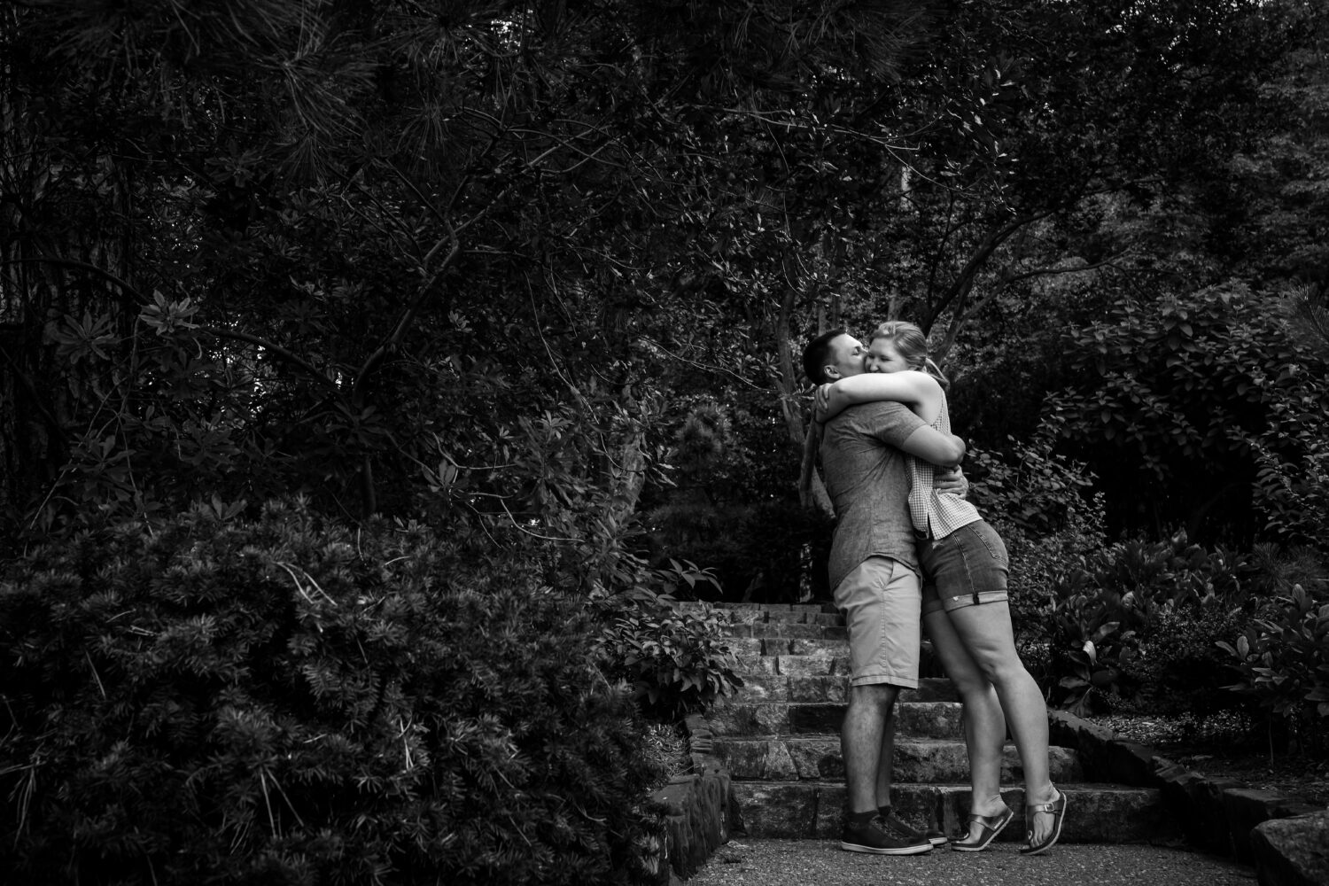 Black and white image captured by proposal photographer, lisa Rhinehart, of the couple hugging one another after the proposal inside of the Missouri botanical gardens 