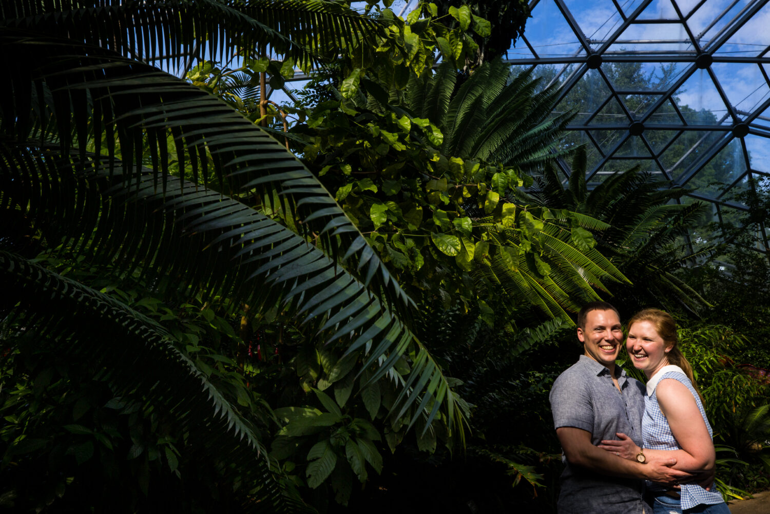 missouri botanical gardens proposal photographer, lisa rhinehart, captures this creative, vibrant, fun, unique image of the couple as they embrace one another and are laughing and smiling amongst the various plants inside the garden