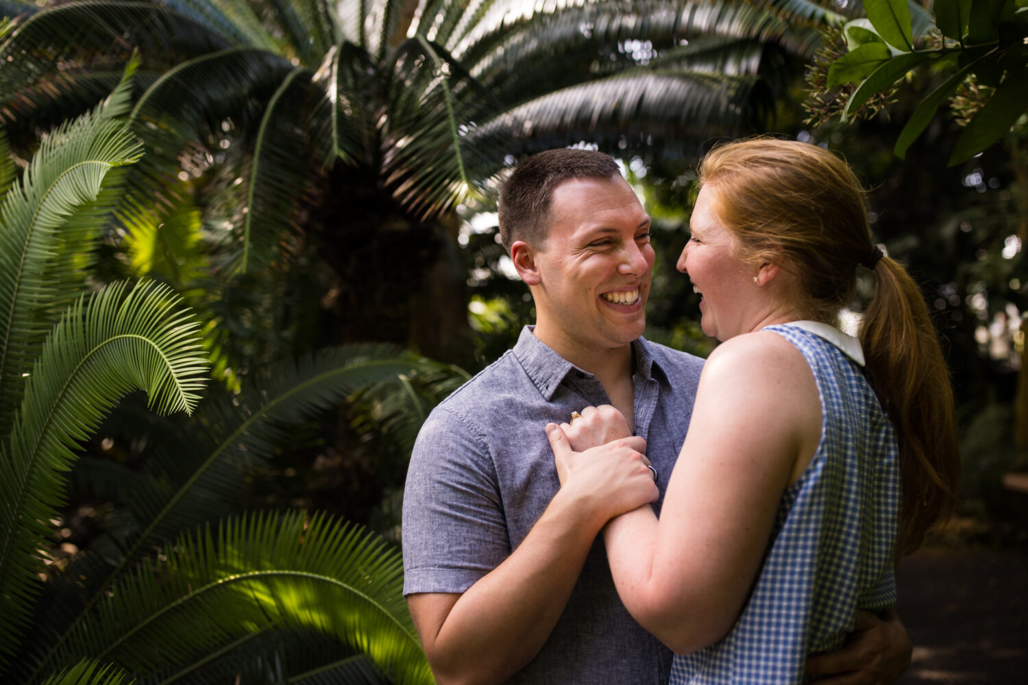 authentic proposal photographer, lisa rhinehart, captures this authentic image of the couple hugging and holding hands as they are laughing and smiling at one another inside of the garden 