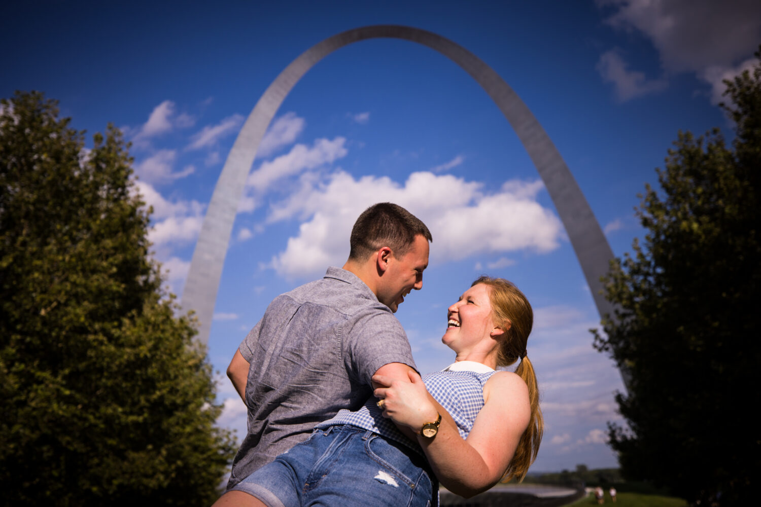 st louis missouri proposal photographer, lisa rhinehart, captures this fun, authentic, creative image of the couple as the guy dips the girl backwards as they stand underneath the archway 