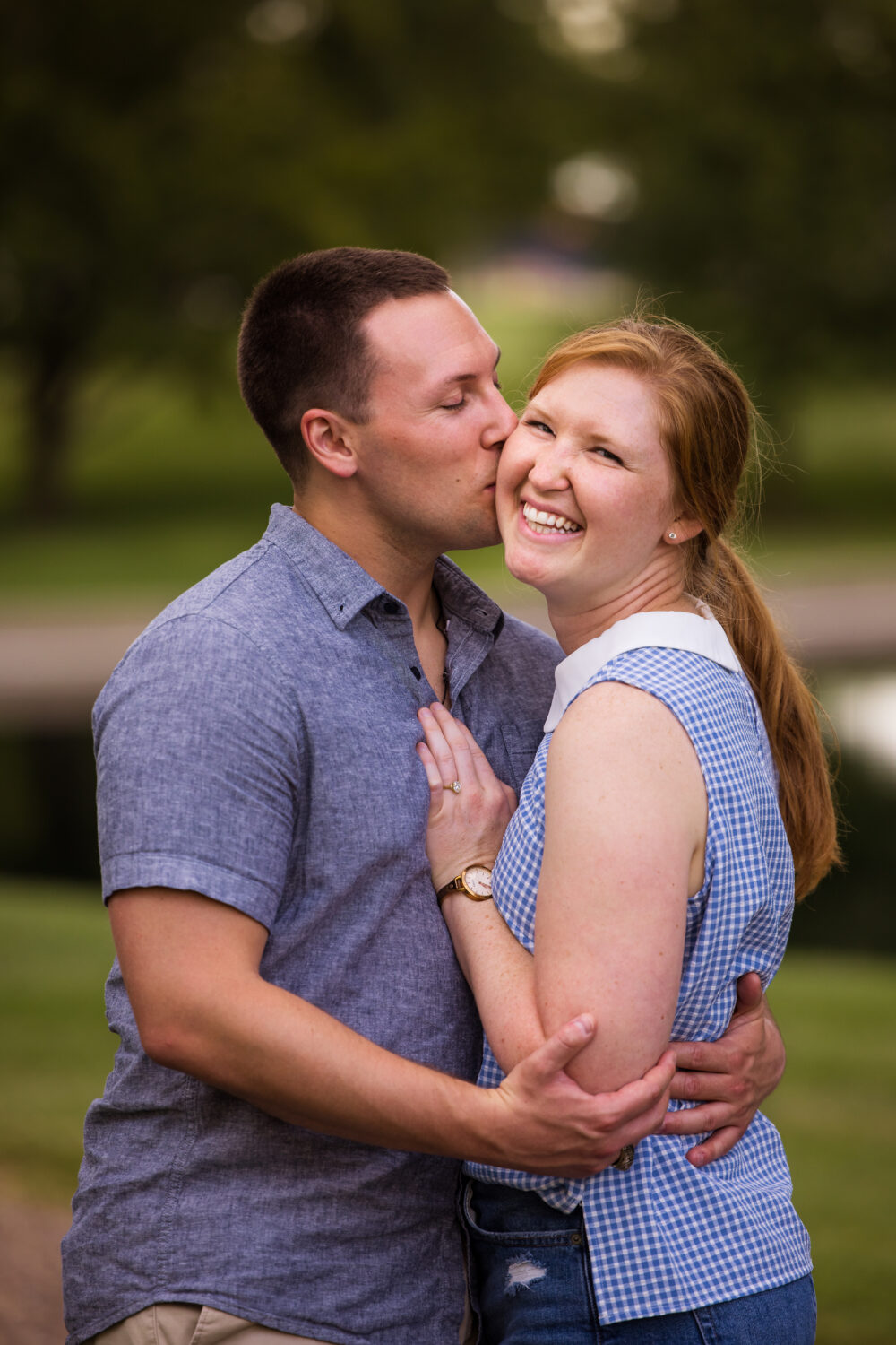 traditional image of the couple embracing one another and showing off the new ring and smiling from ear to ear as he kisses her on the forehead captured by surprise proposal photographer, lisa rhinehart at the Missouri botanical gardens 
