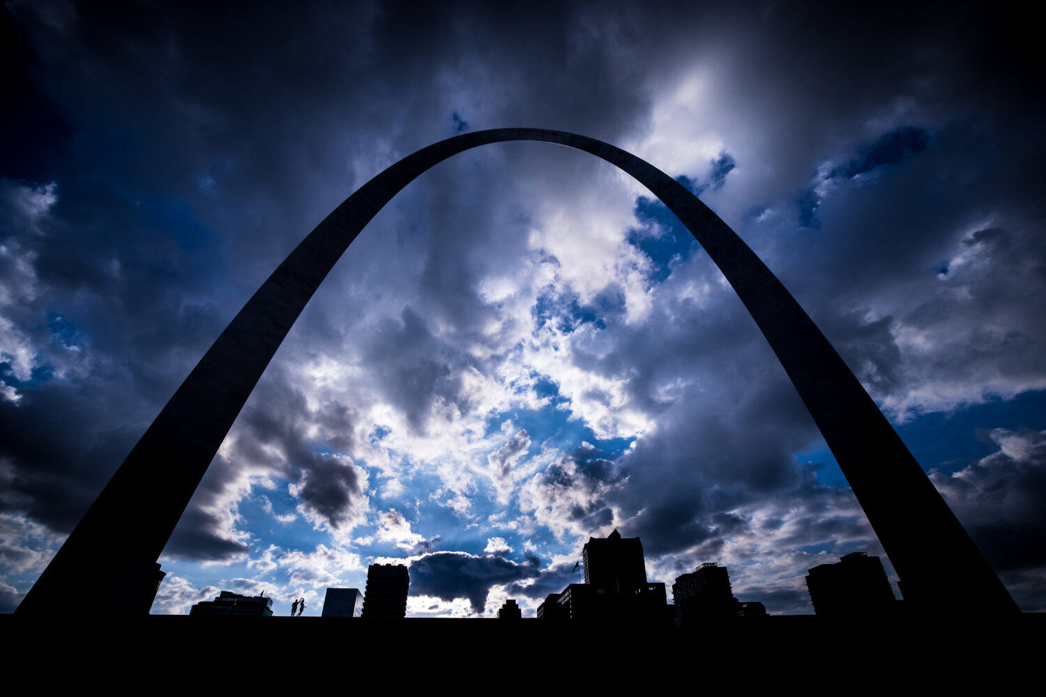 Creative Proposal Photographer, lisa rhinehart, captures this creative, fun, unique image of the couple as they hold hands and spin around underneath the archway as a storm gets ready to roll in to st louis