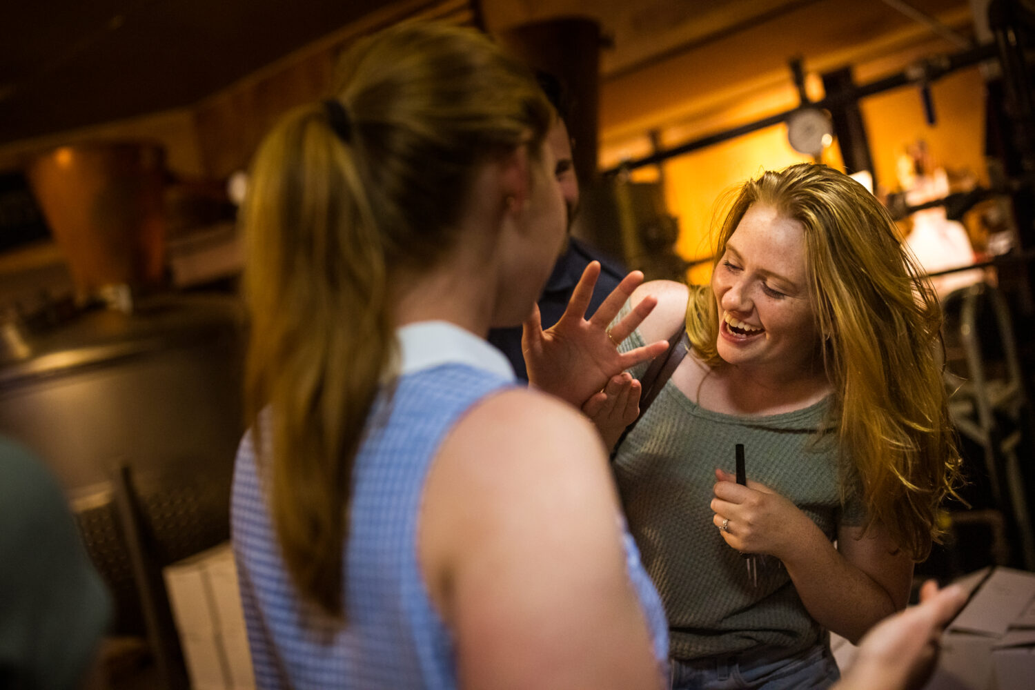 lisa rhinehart, captures this fun image of the girl showing off her ring to her friends at her surprise engagement party after her surprise proposal