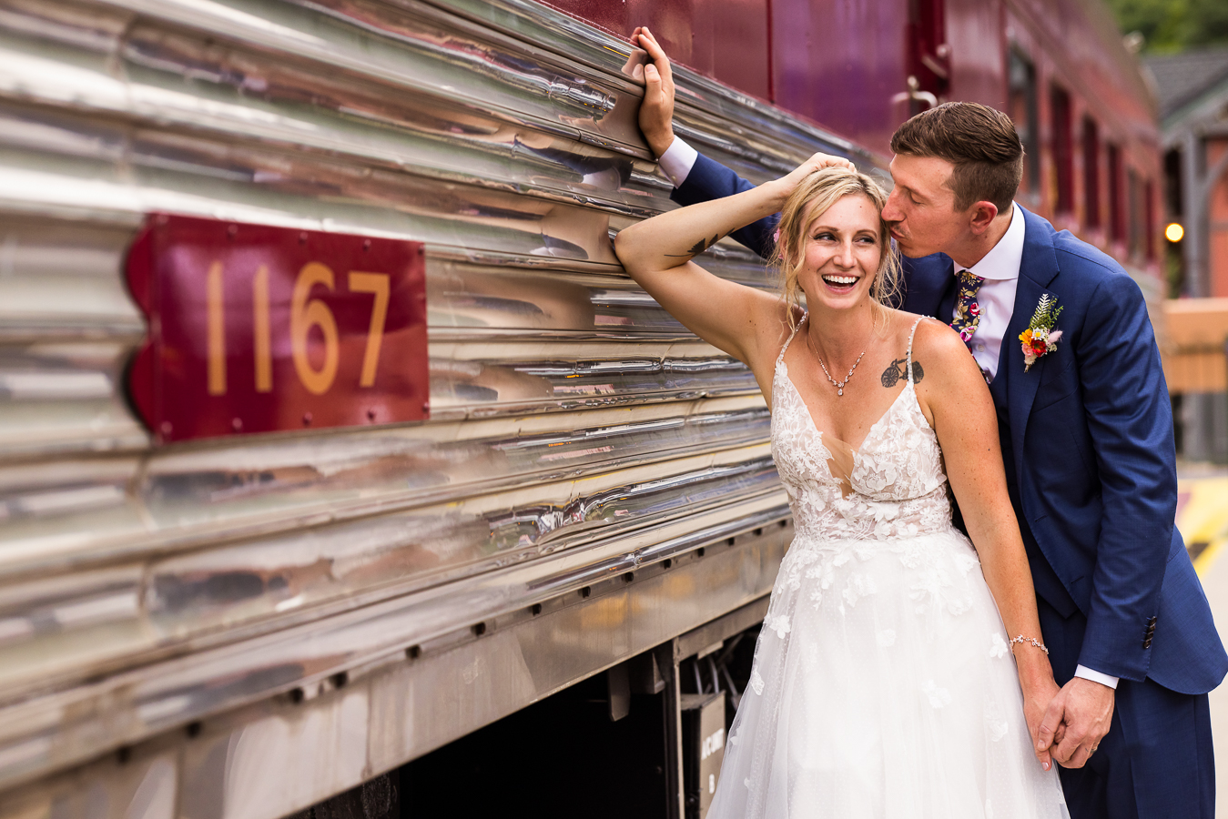 Jim Thorpe Wedding Photographer, lisa rhinehart, captures this fun, creative image of the bride standing against the train car as the groom kisses her on the forehead after their wedding ceremony