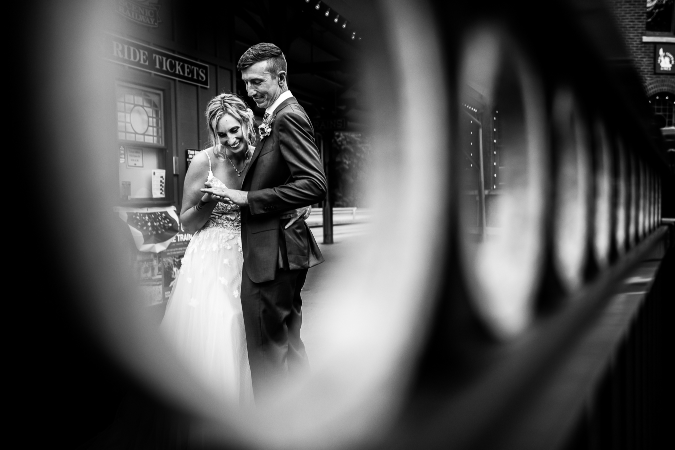 Creative wedding photographer, lisa rhinehart, captures this creative, unique black and white image of the bride and groom looking at each others rings caught through circles on the raining for a unique, creative perspective 
