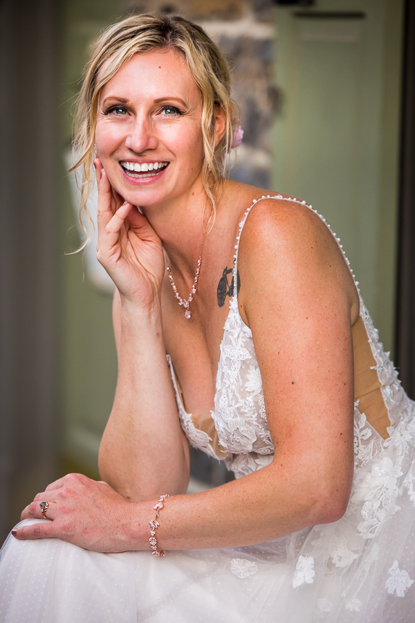 micro wedding photographer, lisa rhinehart, captures this traditional portrait of the bride with her hand touching her face smiling at the camera 