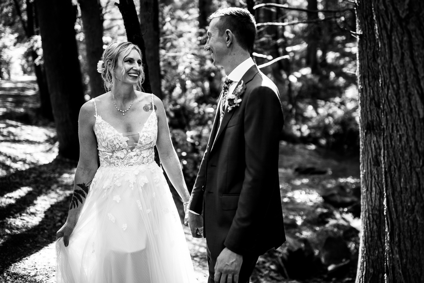 black and white image of the bride and groom seeing each other for the first time during their first look as they hold hands and smile at one another captured by pa wedding photographer, lisa rhinehart
