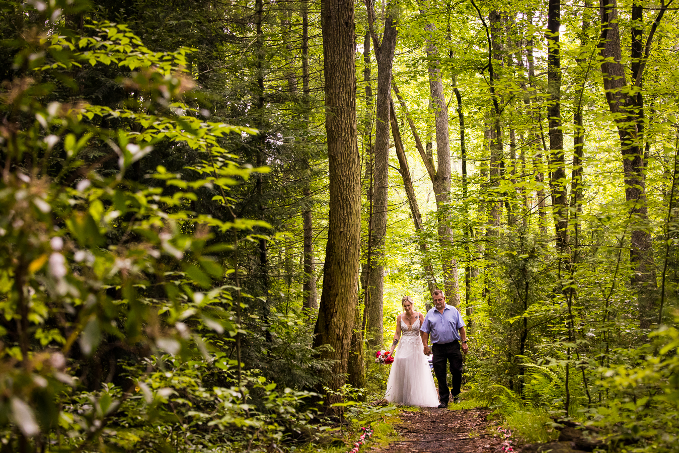 pa wedding photographer, lisa rhinehart, captures this vibrant, unique image of the bride and her father walking down the hiking trail as they make their way to the groom 