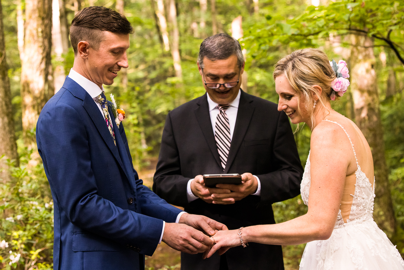 vibrant, colorful image of the groom placing the ring onto his brides finger as they stand underneath the trees on a hiking trail for their intimate wedding ceremony captured by micro wedding photographer, lisa rhinehart