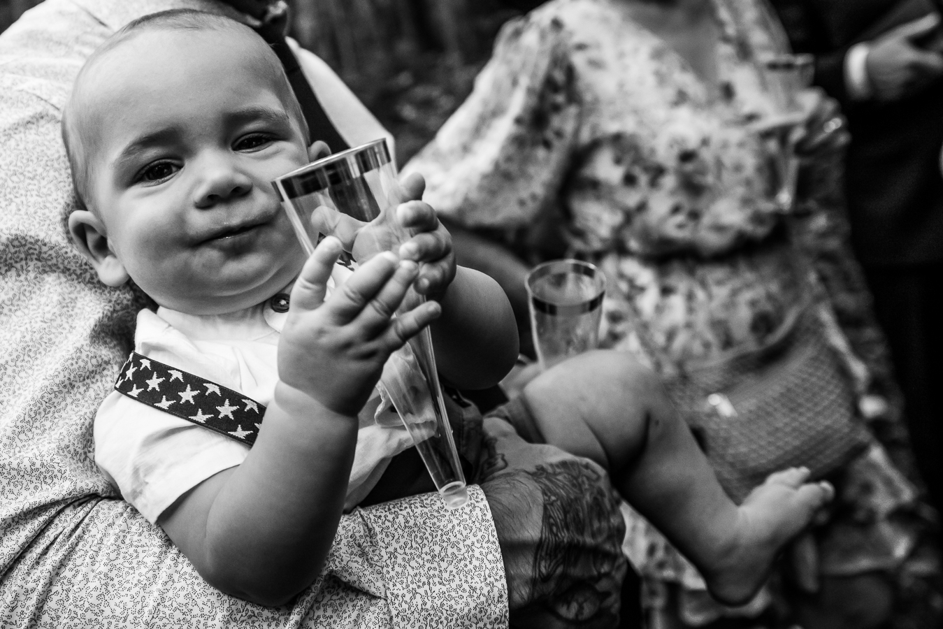 black and white image of a baby holding the cup during the start of this micro wedding reception 