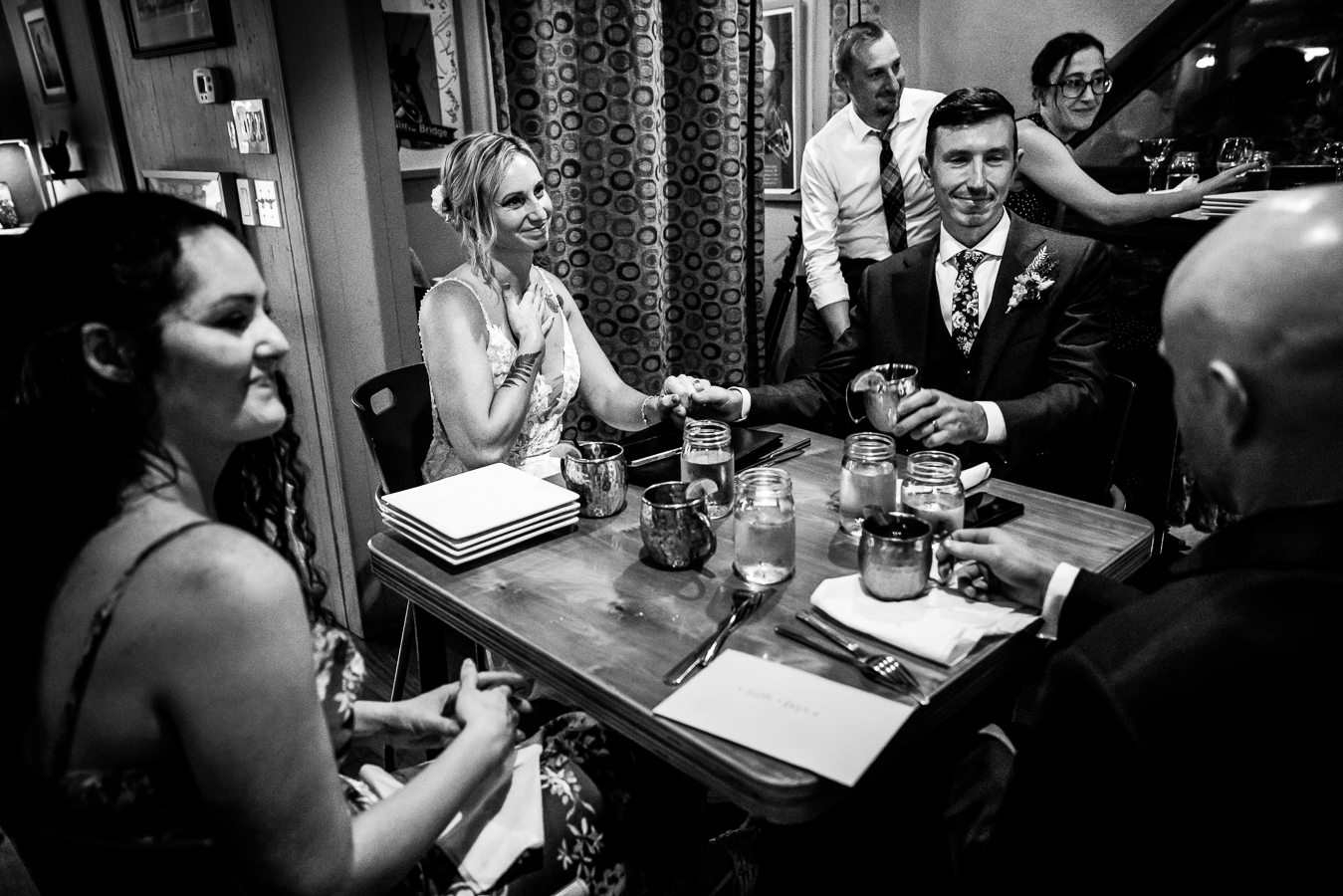authentic wedding photographer, lisa rhinehart, captures this black and white image of the bride with her hand on her chest as she is touched by what her guests are saying during their speeches and toast at this cafe arielle wedding reception 