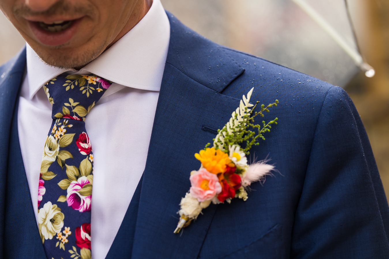 best pa wedding photographer, lisa rhinehart, captures this close up image of the grooms vibrant blue tux covered in tiny rain droplets with his colorful tie and boutineer on his chest