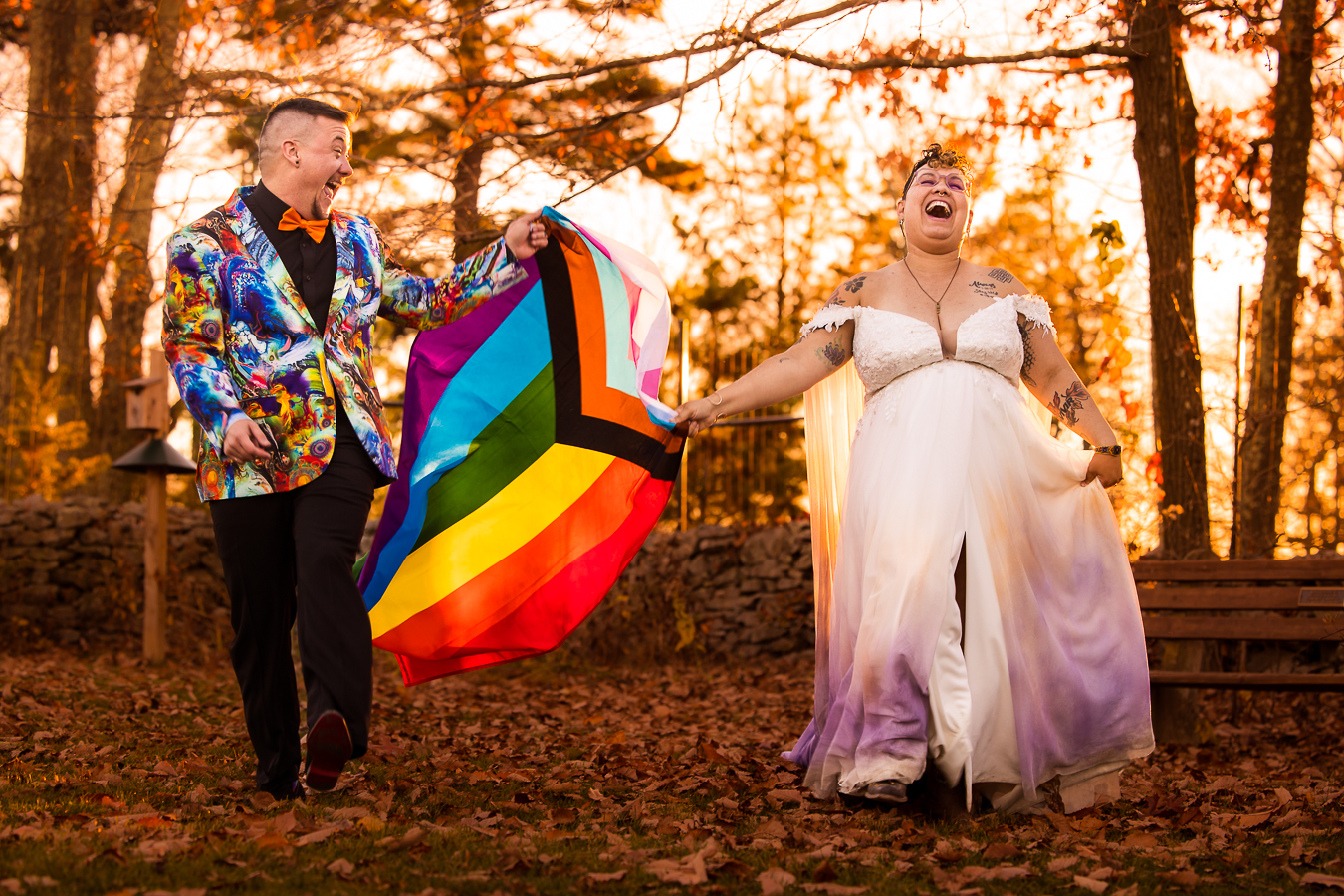 washington dc lgbtq inclusive wedding photographer, lisa rhinehart, captures the couple as they walk with joy through the woods holding their rainbow flag smiling and laughing with one another 