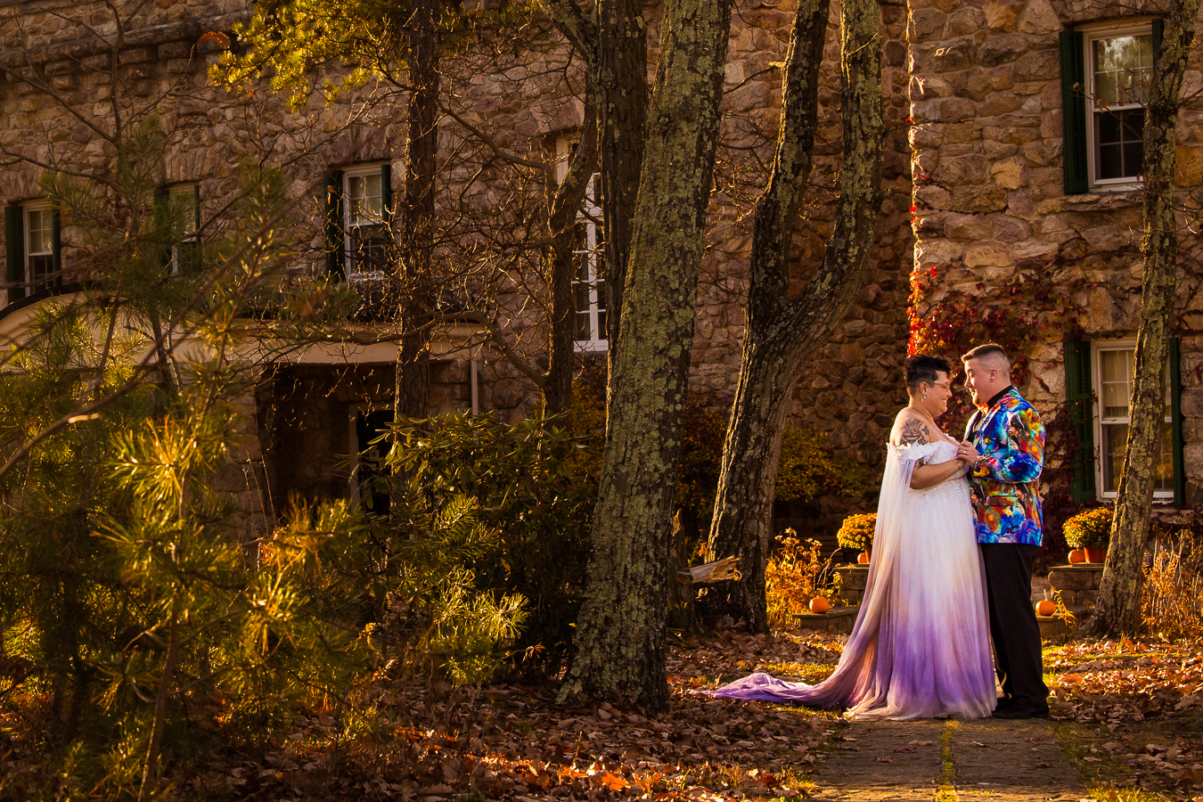 kings gap mansion photographer, lisa rhinehart, captures this image of the couple standing in front of the stone mansion in their vibrant, colorful wedding attire during their after session 
