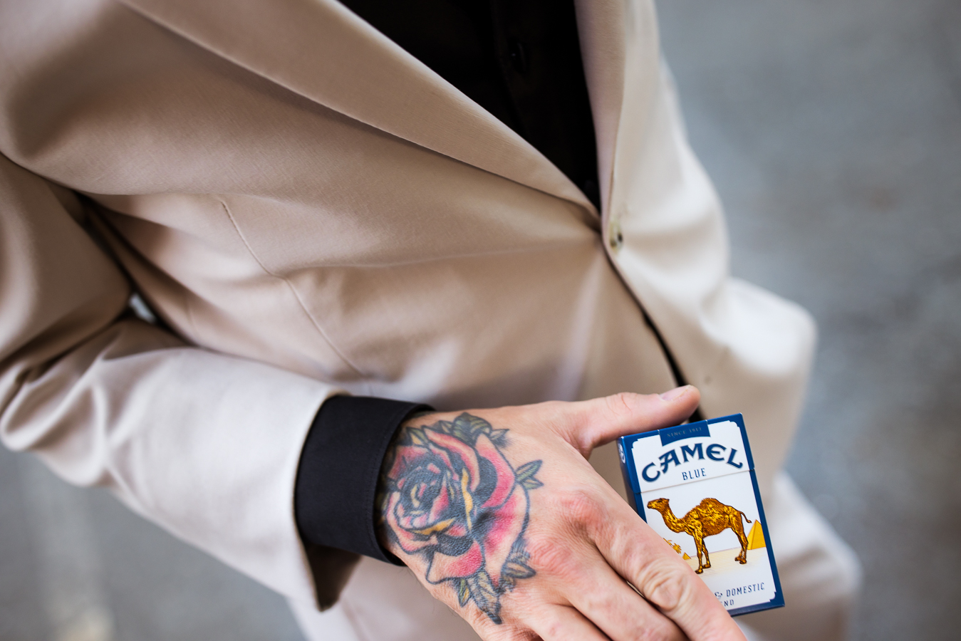 Close up image of the grooms rose tattoo as he hold his cigarettes in his hand during his pre ceremony portraits 