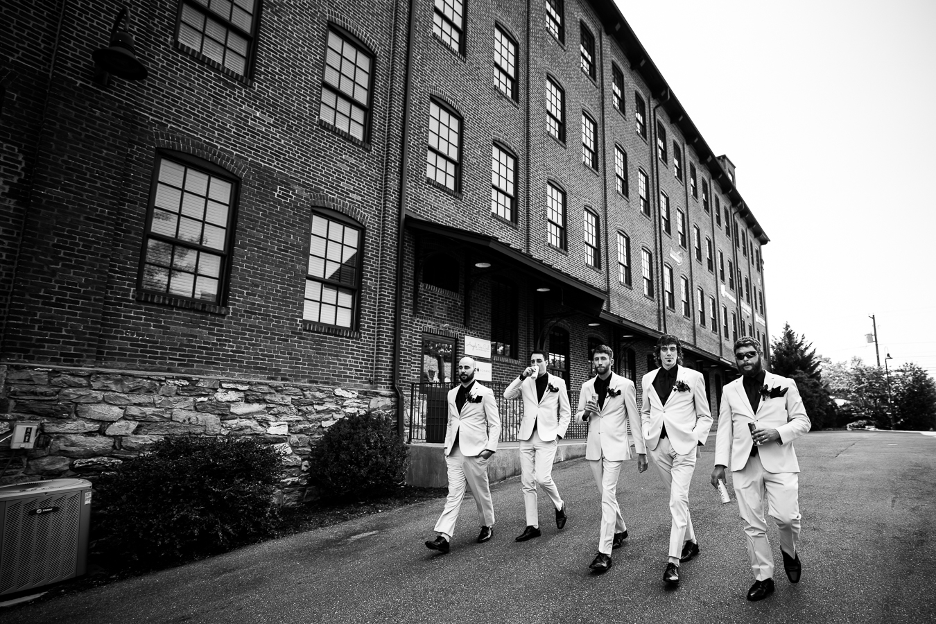 Cork Factory Hotel Wedding Photographer, lisa rhinehart, captures thi black and white image of the groom and his groomsmen as they walk down the street outside of the hotel before the wedding ceremony in lancaster
