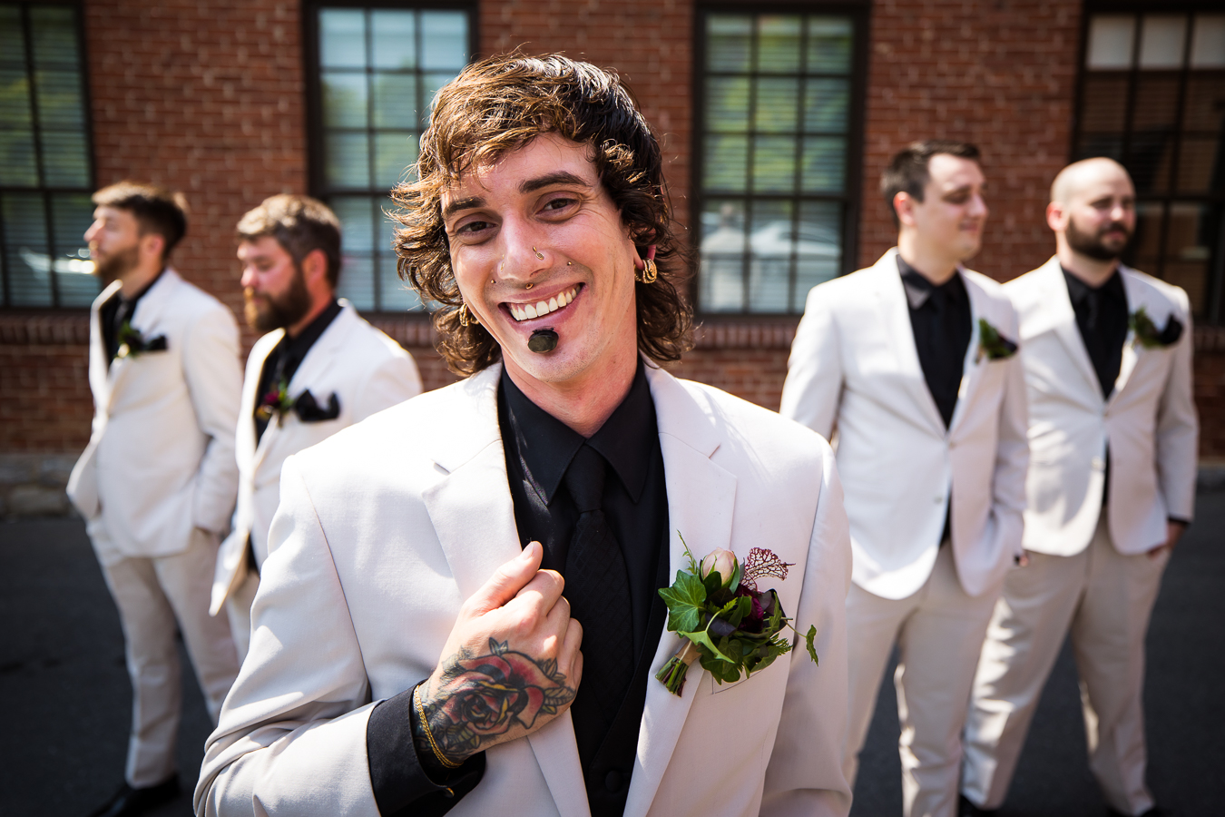 best pa wedding photographer, lisa rhinehart, captures this close up image of the groom smiling at the camera as his groomsmen stand behind him outside of the hotel 