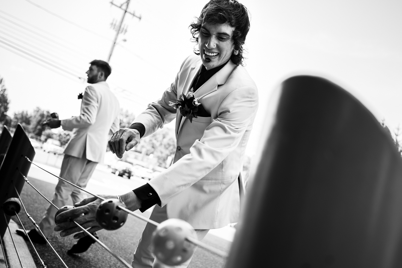 black and white image of the groom playing with the railing at the hotel as they get their wedding party photos outside 