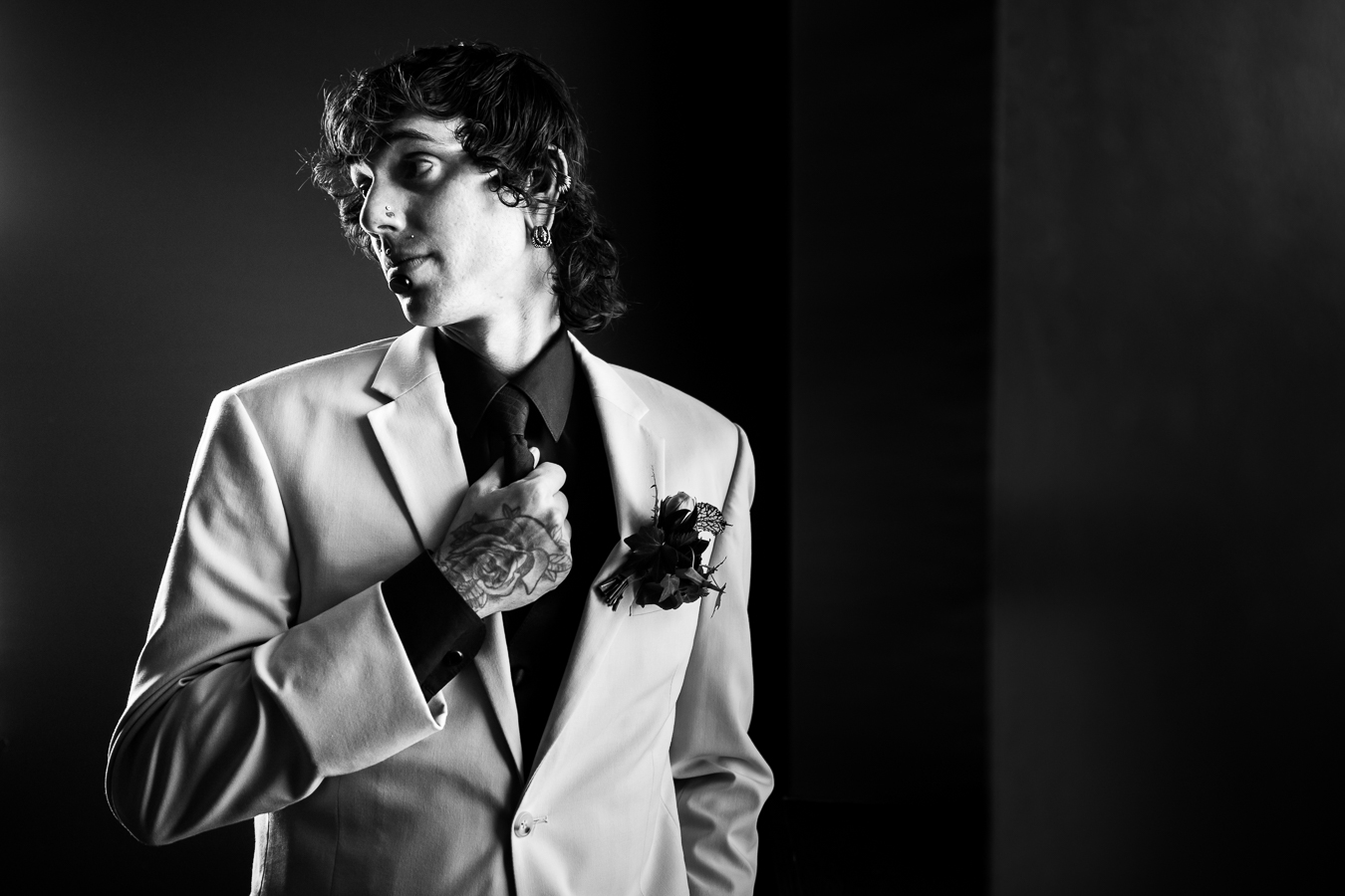 Cork Factory Hotel Wedding Photographer, lisa rhinehart, captures this black and white image of the groom looking off into the distance as he grabs his tie showing off his rose tattoo 