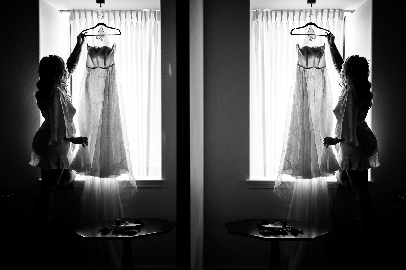 black and white image of the bride showing off her dress as it hangs in the window light in the wedding suite at her lancaster wedding venue 