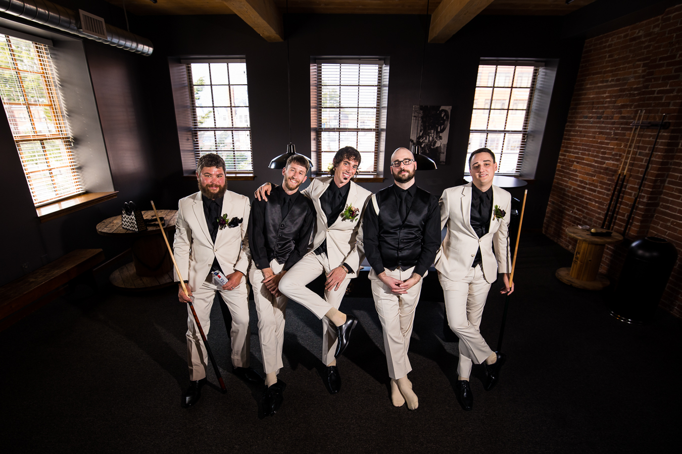 image of the groom with his groomsmen leaning against the pool table inside of the cork factory hotel 