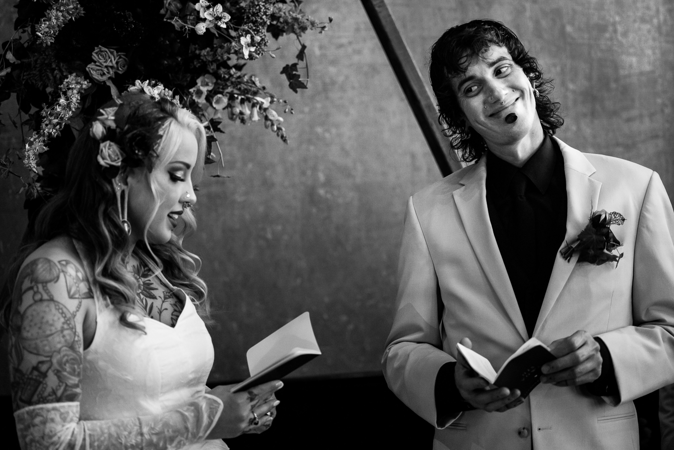 Cork Factory Hotel Wedding Photographer, lisa rhinehart, captures this black and white image of the groom smiling from ear to ear as he looks at his bride reading her vows to him during their wedding ceremony 