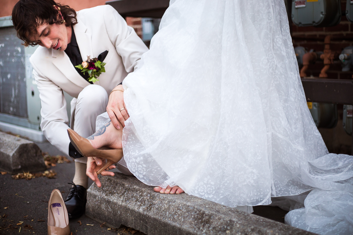 image of the groom putting on the shoes for the bride outside of the hotel in Lancaster 