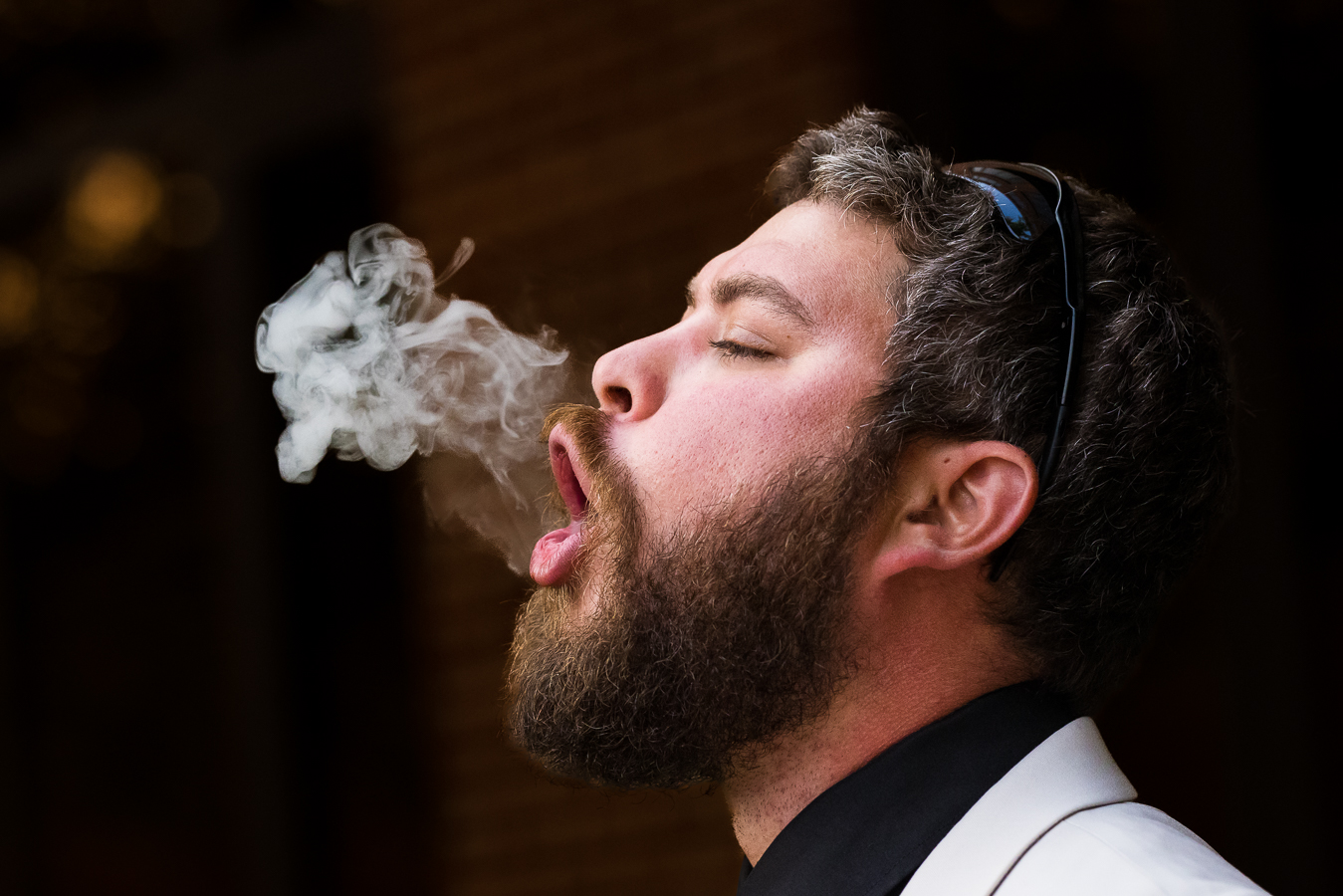 creative Cork Factory Hotel Wedding Photographer, lisa rhinehart, captures this unique image of a groomsmen as he blows smoke into their air before heading into the reception 