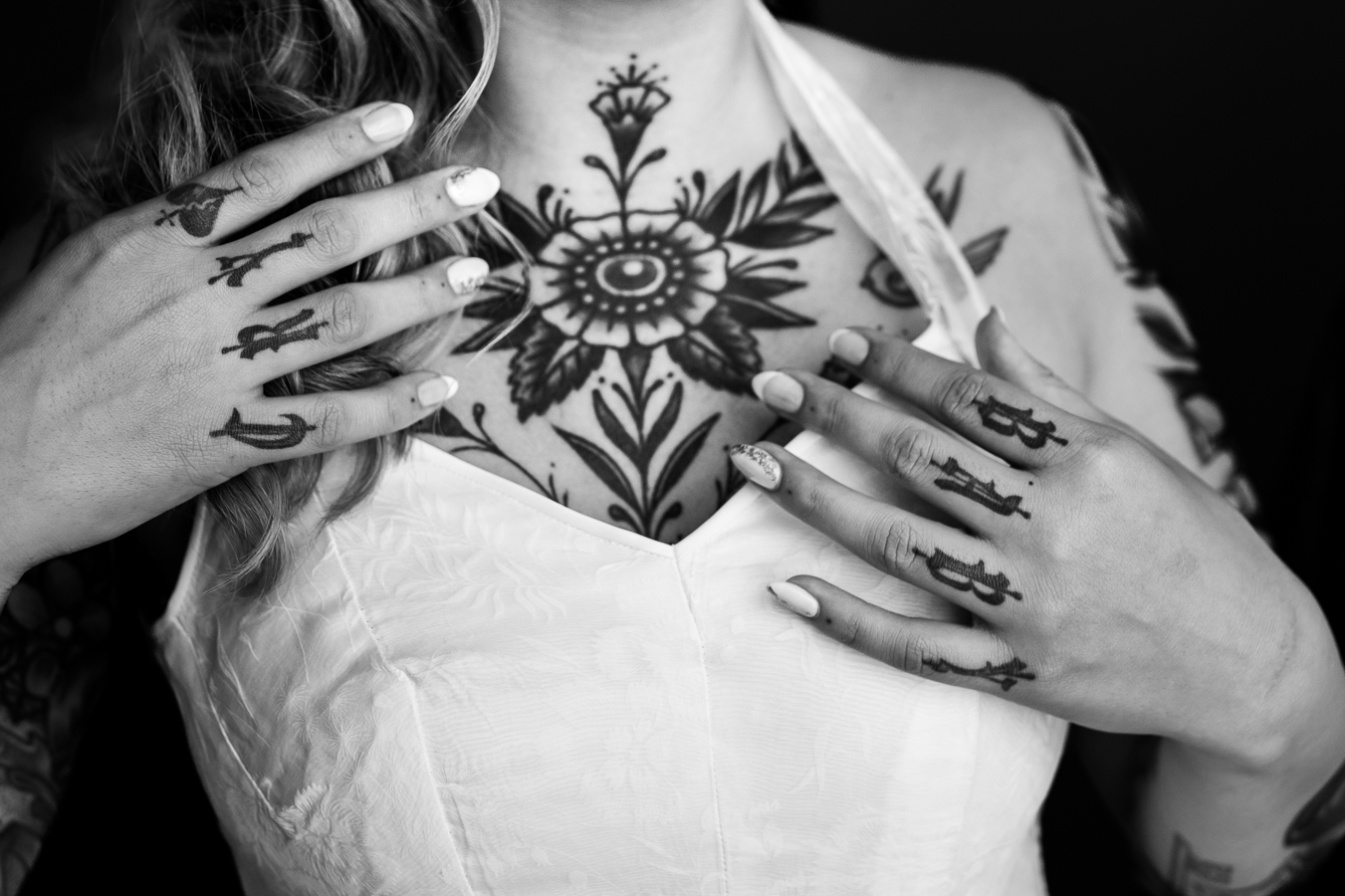 black and white image of the bride showing off her chest and finger tattoos during her wedding preparations