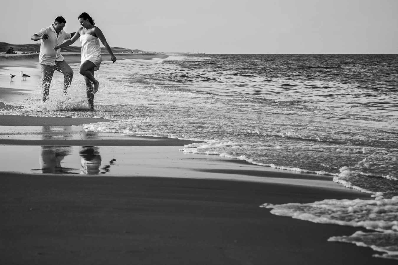 New Jersey photographer, lisa rhinehart, captures this black and white image of the couple as they play and splash around in the ocean water during their engagement shoot