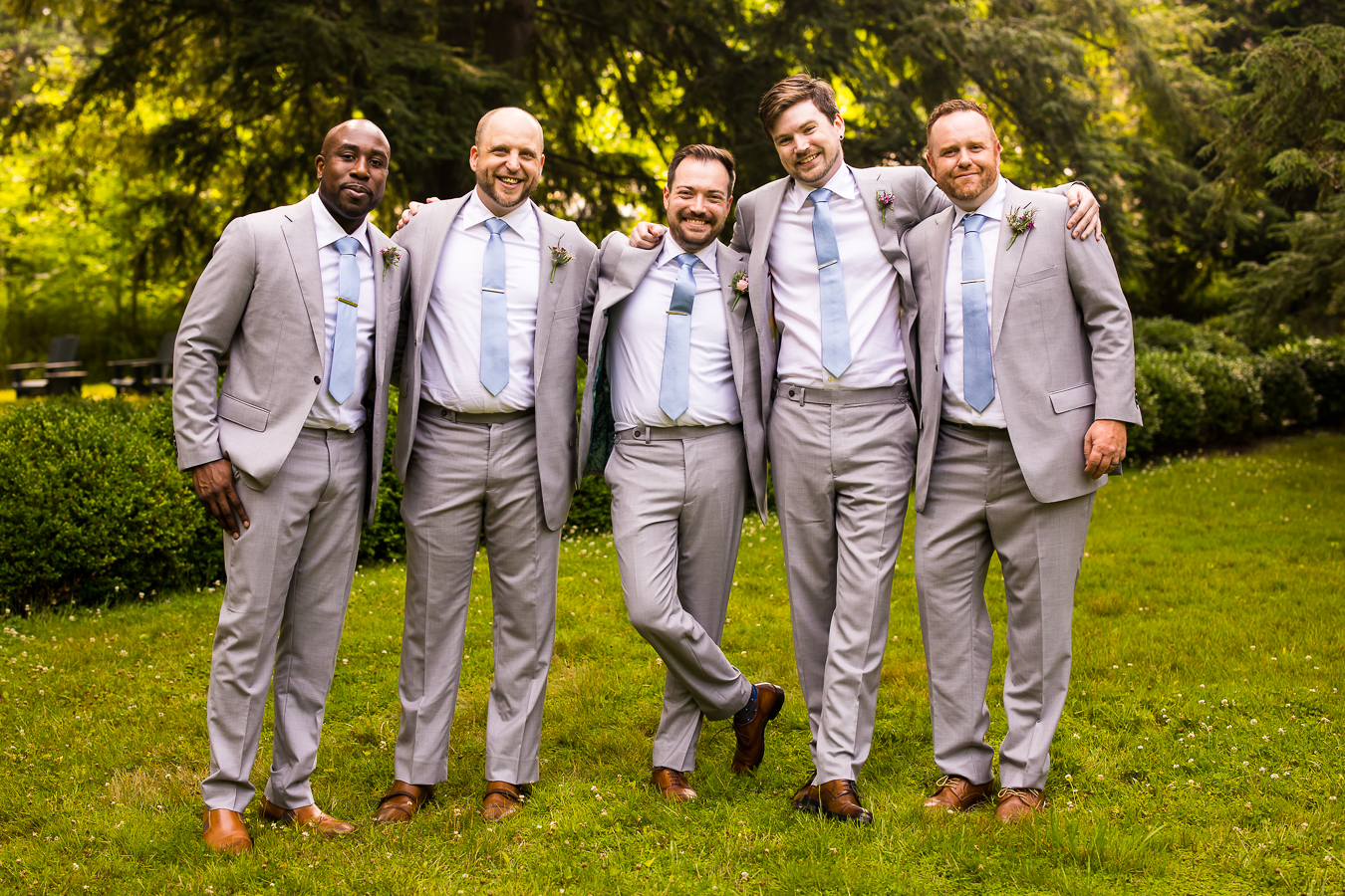 candid photographer, lisa rhinehart, captures this image of the groom with her groomsmen laughing and smiling at the camera in a relaxed line 