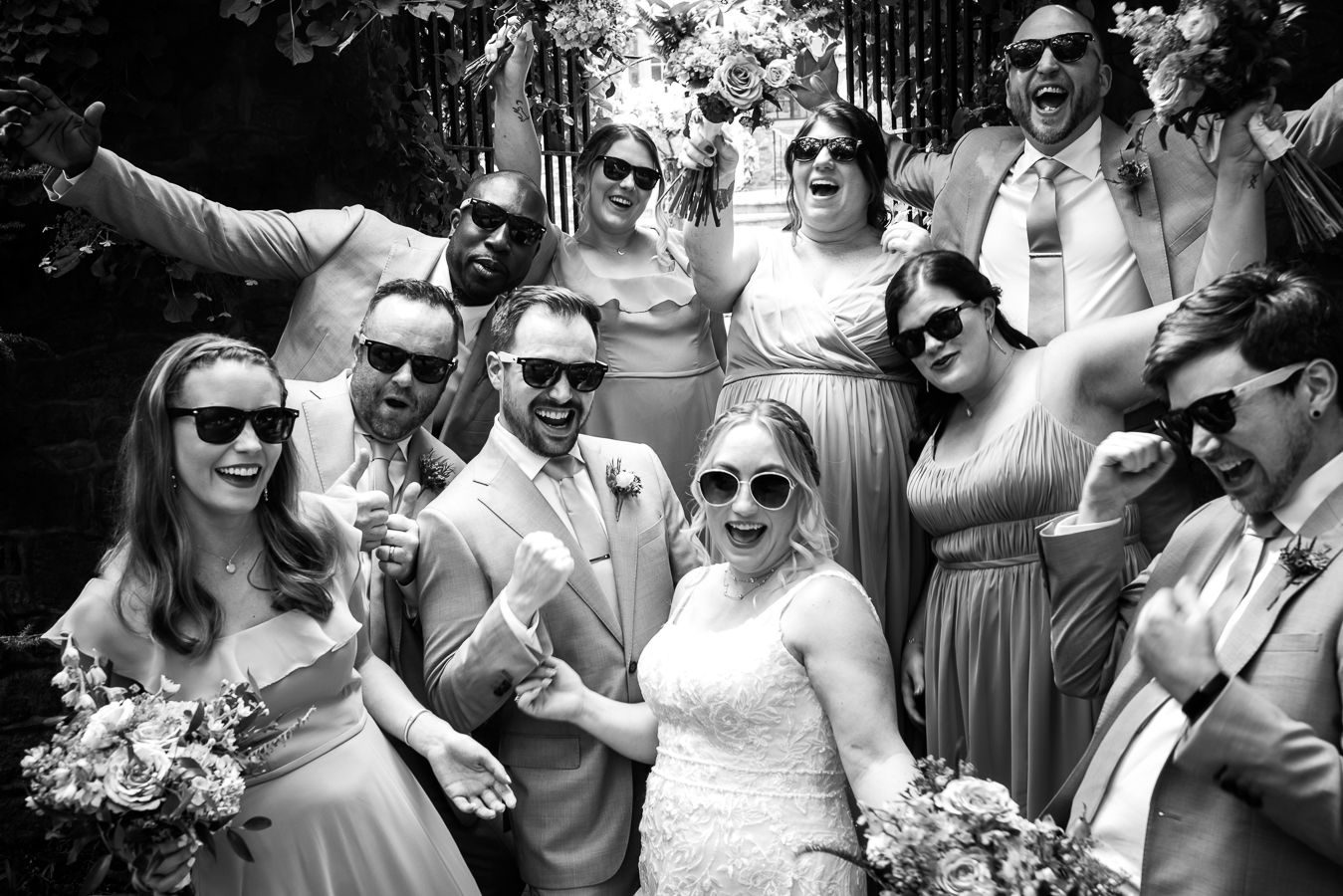 black and white image of the bride and groom with the wedding party all wearing sunglasses for a fun, unique image