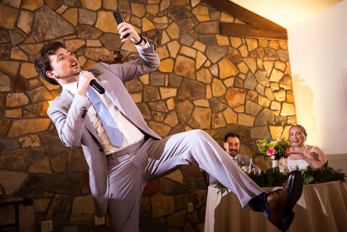 fun image of the brother of the groom giving his speech with his leg in the air during the wedding reception in new hope pa 