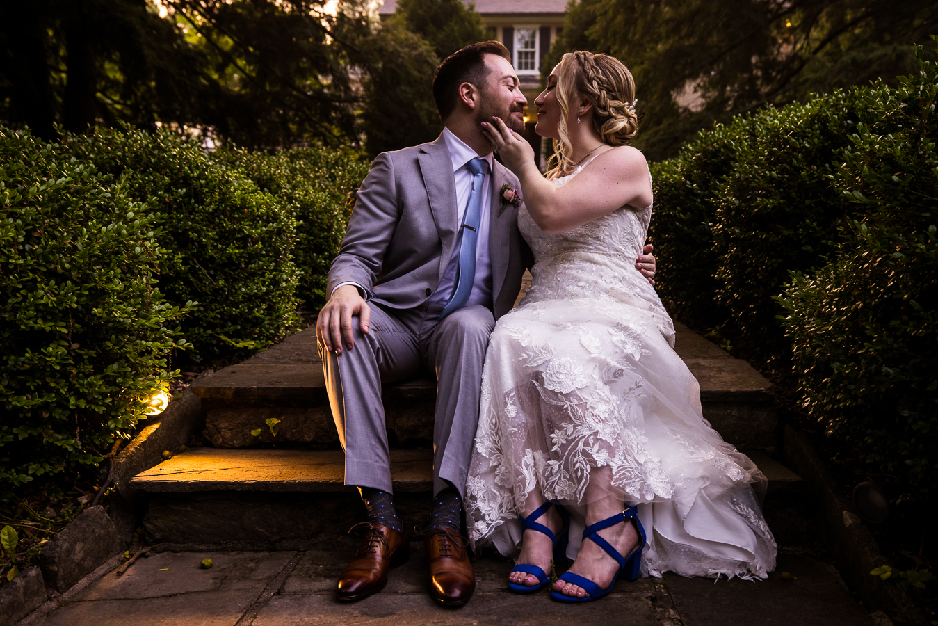 Holly Hedge Estate Wedding Photographer, lisa rhinehart, captures this fun, loving image of the bride and groom as they sit together on the stone walkway smiling at one another after their wedding ceremony 