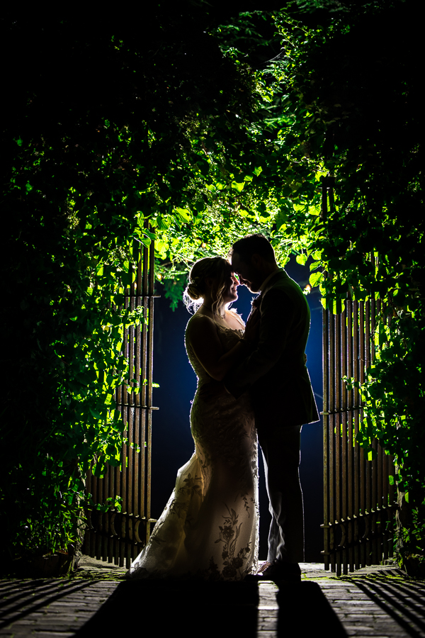 Holly Hedge Estate Wedding Photographer, lisa rhinehart, captures this creative image of the bride and groom as they stand in front of the gate surrounded by greenery with their heads together 