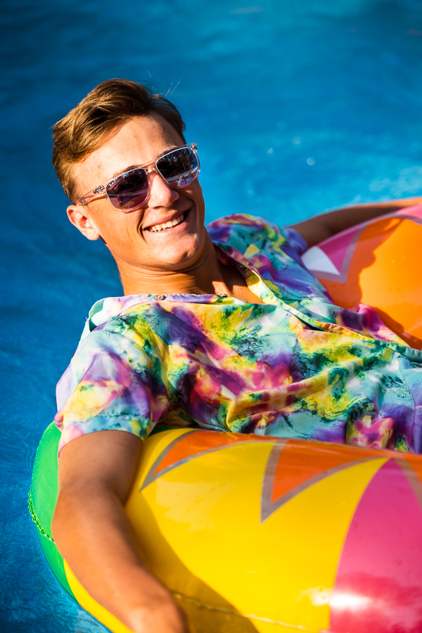 lisa rhinehart, captures this image of this senior as he floats around in his pool wear a vibrant outfit in a colorful floaty in shippensburg pa 