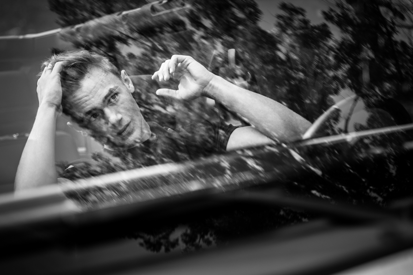 Creative Senior Portrait Photographer, lisa rhinehart, captures this black and white unique creative reflection image of this senior fixing his hair in the window of his car during this senior session in Chambersburg pa 