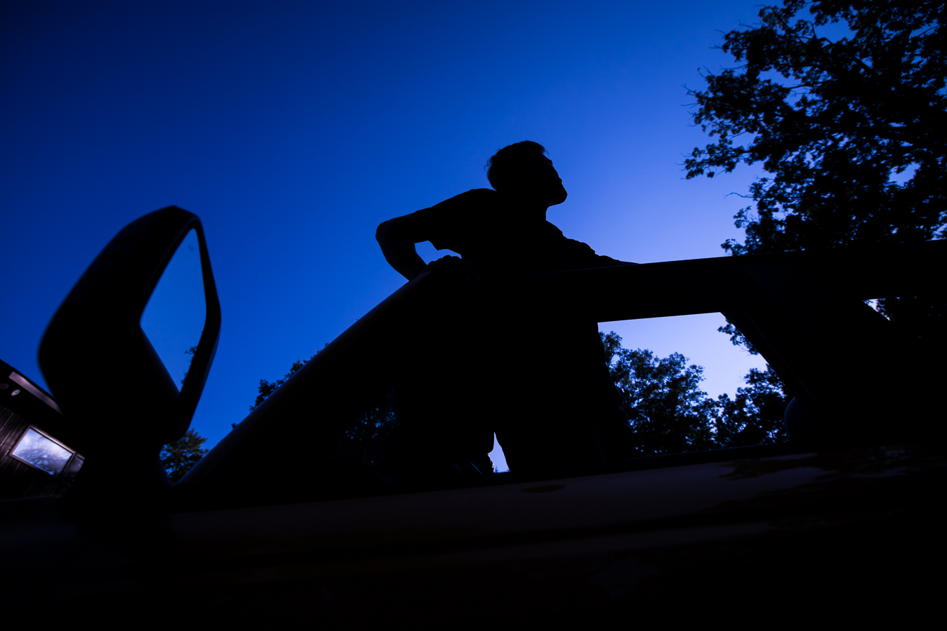 vibrant blue and purple image of this senior as he looks up into the sky while standing in his jeep during sunset captured bylisa rhinehart photographer