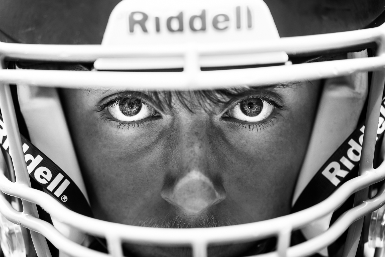 shippensburg pa portrait photographer, lisa rhinehart, captures this close up black and white image of the football player through his helmet during this outdoor football photo session 