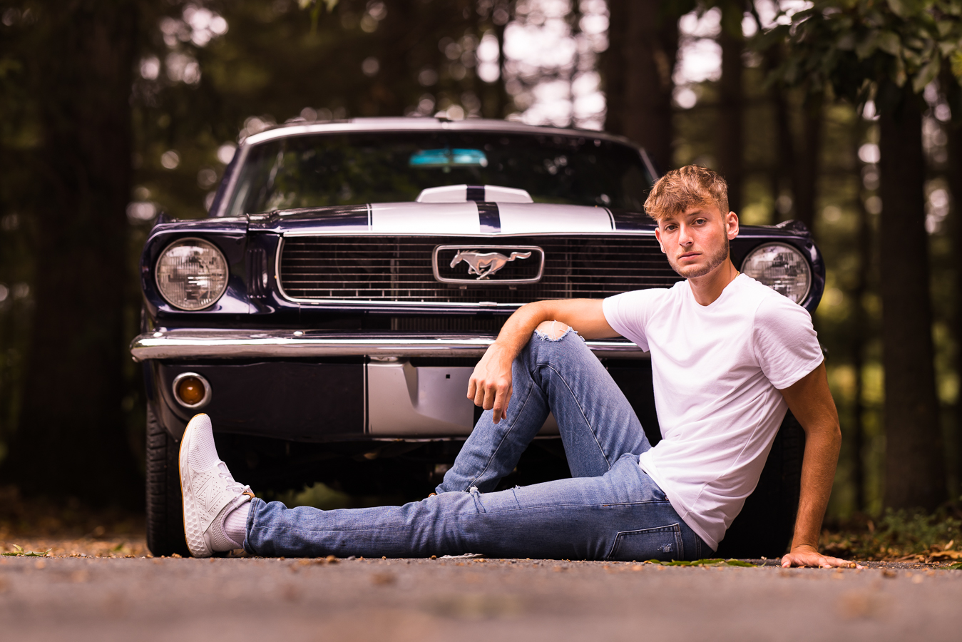 High school Senior Portrait Photographer, lisa rhinehart, captures this image of this senior as he sits in front of his 1966 mustang and shows it off behind him 