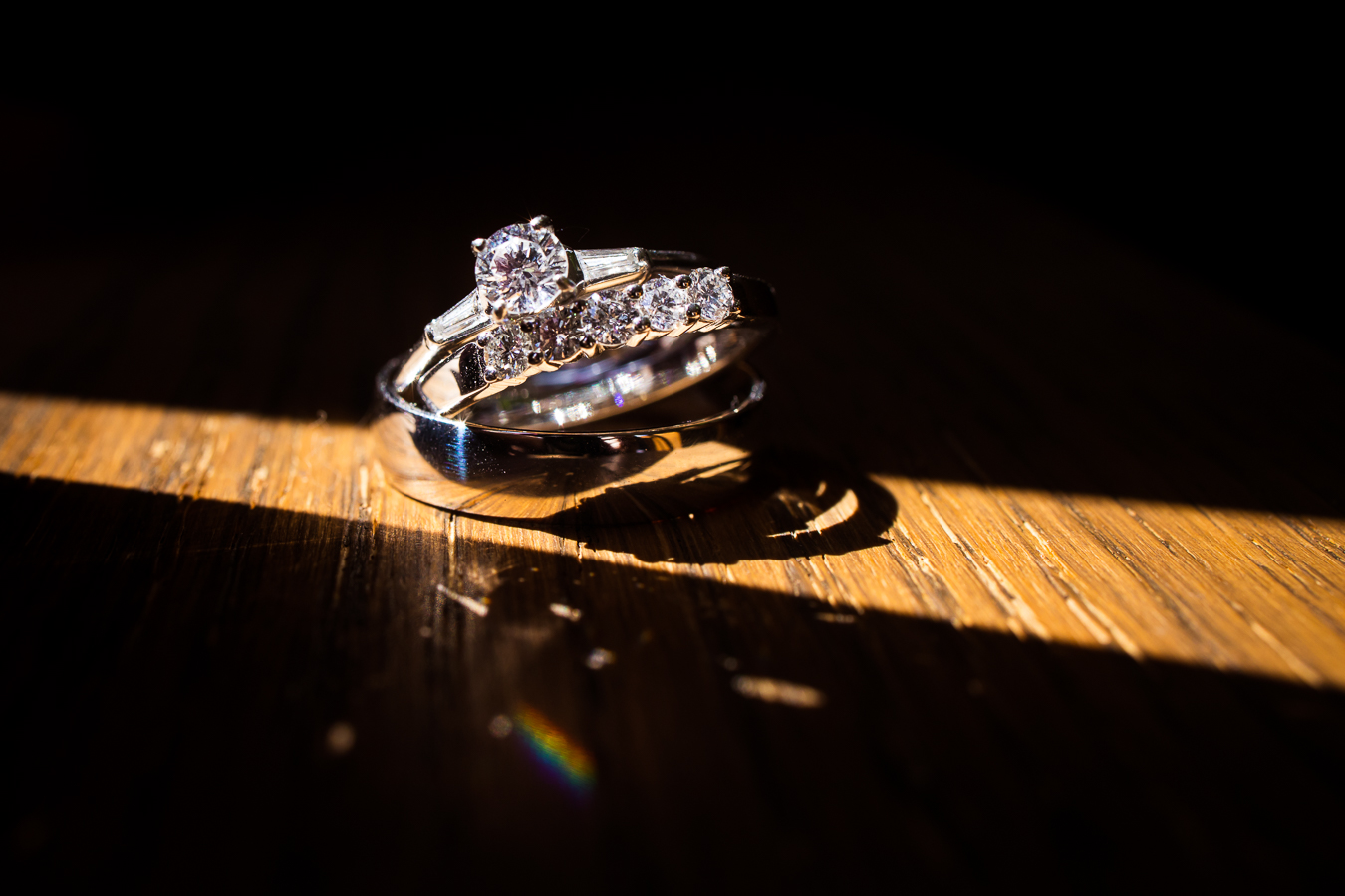 creative stahlstown wedding photographer, Lisa rhinehart, captures this stunning detail photo of this bride and groom's silver wedding rings and bands captured in the single beam of sunlight on the wooden floor