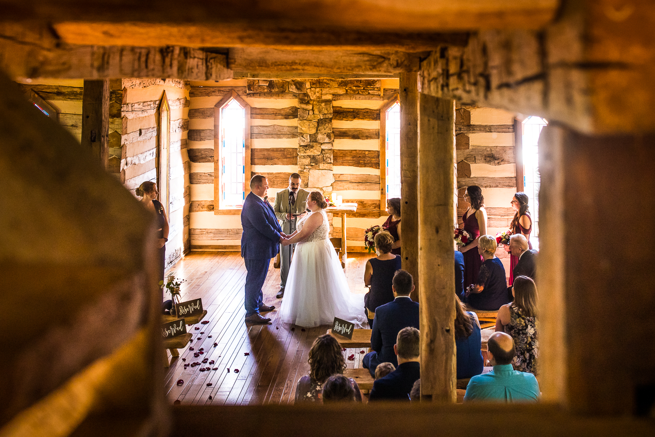 Oak Lodge Wedding Photographer, rhinehart photography, captures this cozy, intimate image of the bride and groom holding hands during their wedding ceremony in this cozy, intimate chapel at oak lodge in stahlstown, pa 