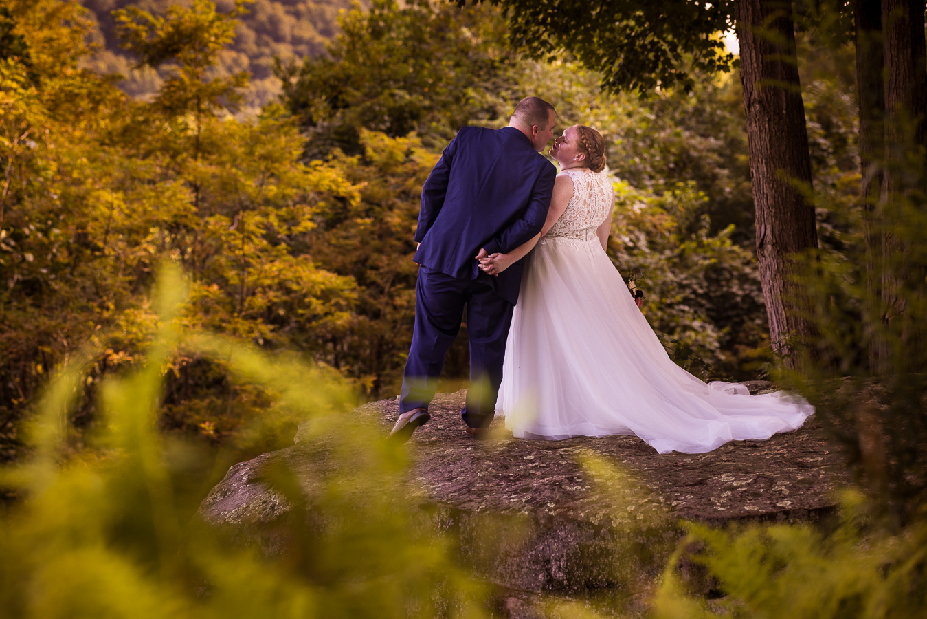 Oak Lodge Wedding Photographer, rhinehart photography, captures this colorful fall image of the bride and groom as they share a kiss on this outdoor overlook surrounded by autumn colored leaves and trees during their outdoor stahlstown, pa wedding