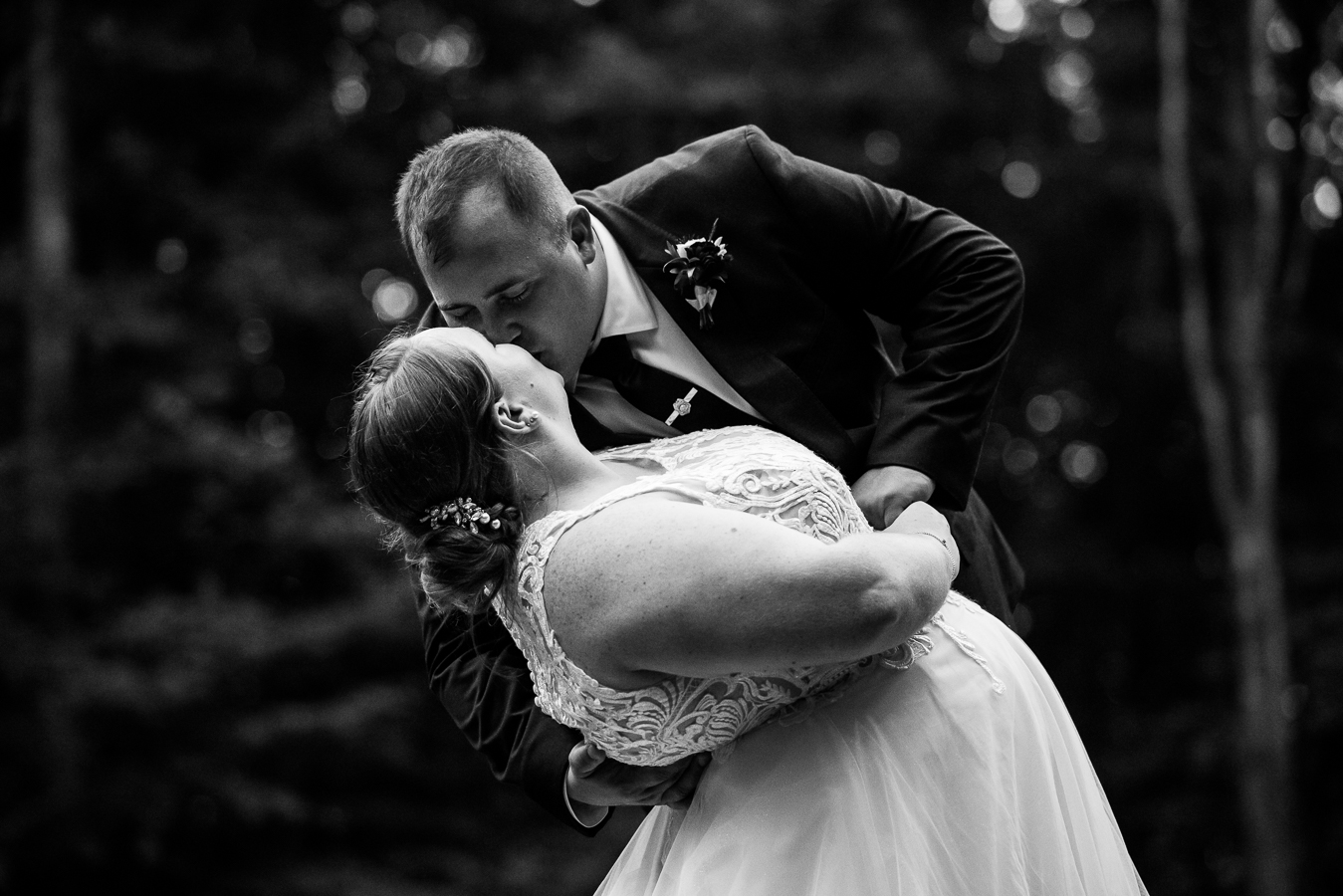 black and white image of the bride and groom as they share a dip and a kiss together out in the middle of the woods after their wedding ceremony in stahlstown, pa 