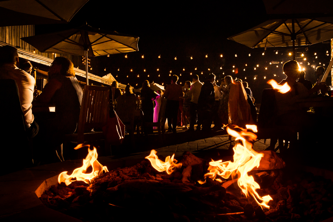 creative Oak Lodge outdoor Wedding Photographer, rhinehart photography, captures this fun image of the wedding reception of family and friends dancing while others gather around the warm fire pit to catch up 