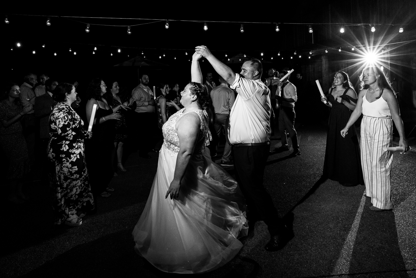 black and white image of the bride and groom as they dance together and spin one another during their fun, unique outdoor wedding reception at the oak lodge in stahlstown pa 