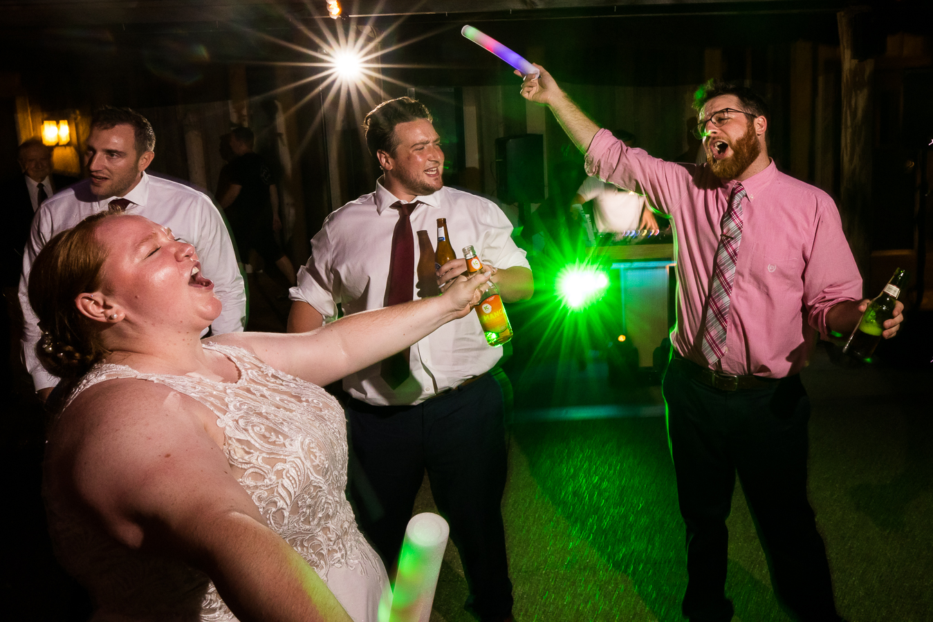 vibrant, colorful, fun image of this outdoor wedding reception as guests sing and dance with the bride and their giant glow sticks