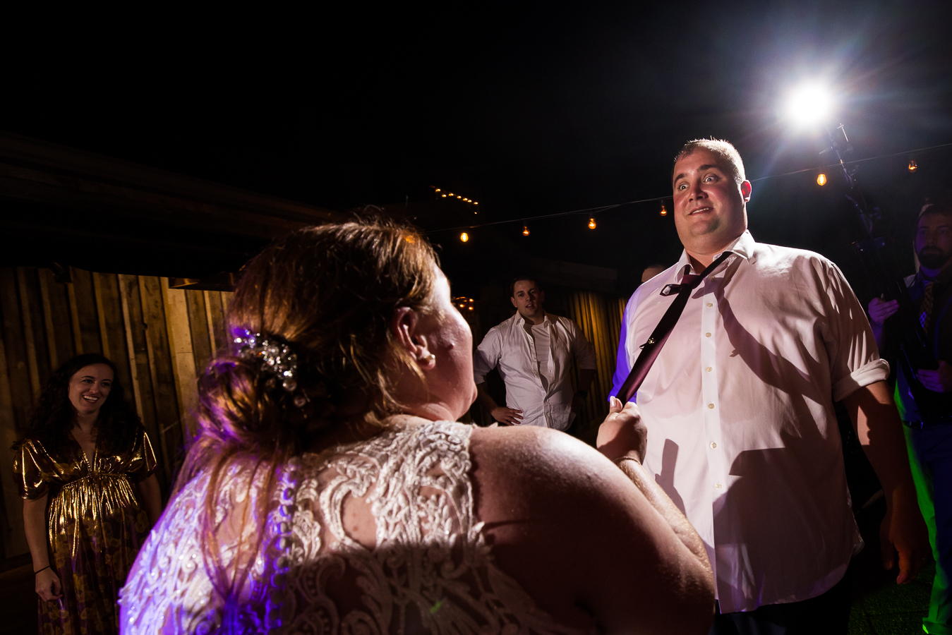 creative, fun image captured by fun reception photographer, lisa rhinehart, from this outdoor wedding reception of the couple as they dance with each other and the brides pulls the grooms tie 