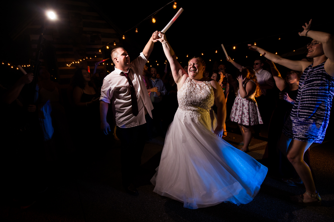 Oak Lodge Wedding Photographer, rhinehart photography, captures this fun end of the night shot of the bride and the groom as they dance together with the giant glowsticks with their families and friends surrounding them 