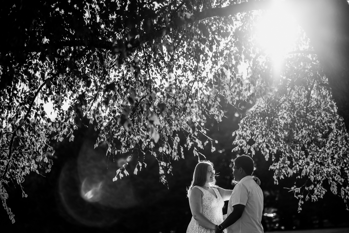 DMV Wedding Photographer, lisa rhinehart, captures this black and white image of the couple during their intimate wedding ceremony in spencerville, Maryland as they hold hands and smile at each other underneath a tree
